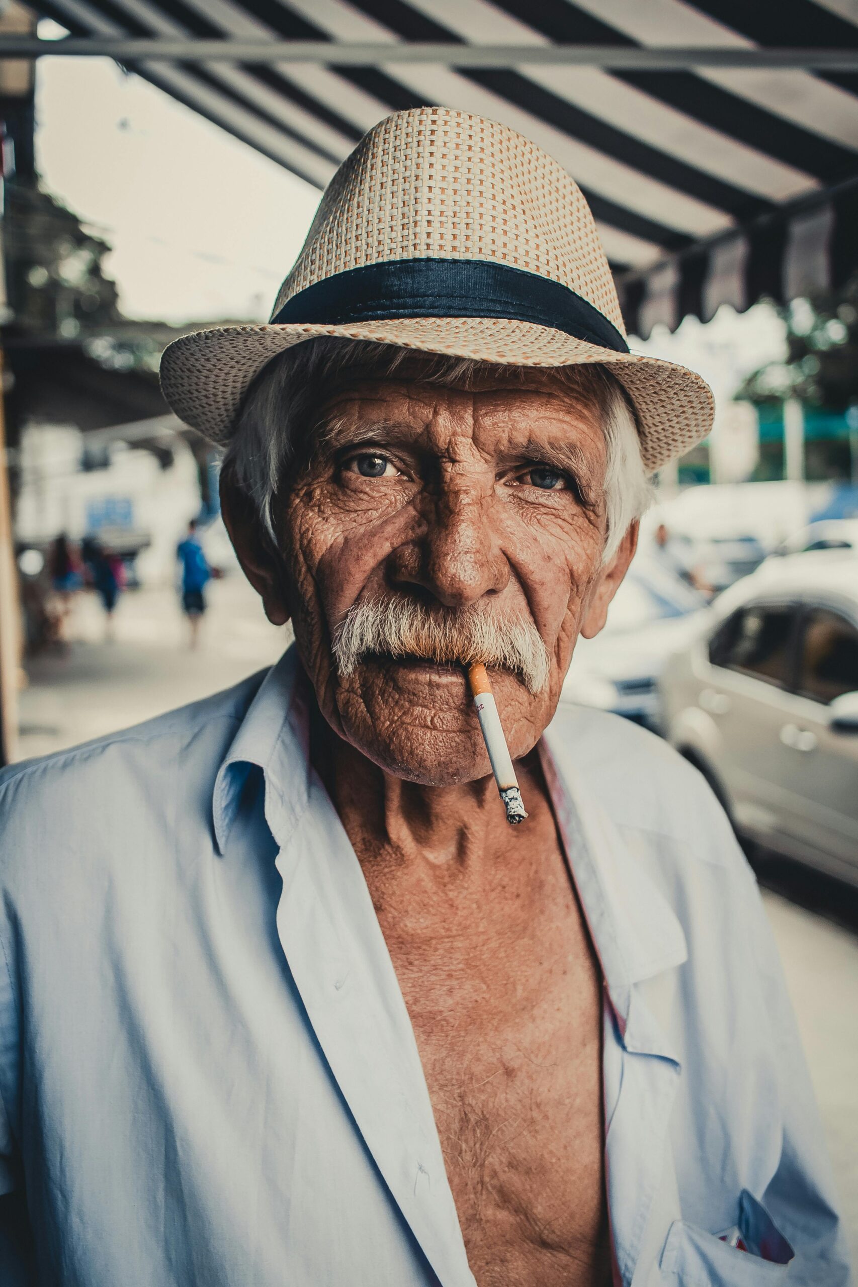 Portrait of an elderly man wearing a hat and smoking in São Paulo's streets, Brazil.